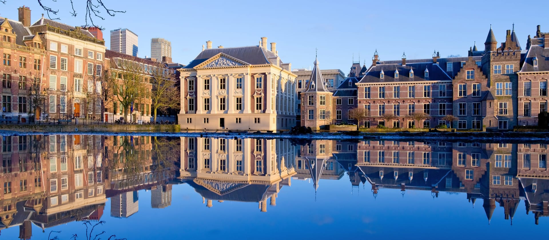Historische gebouwen aan een waterkant met reflecties in het water in Den Haag, Nederland.